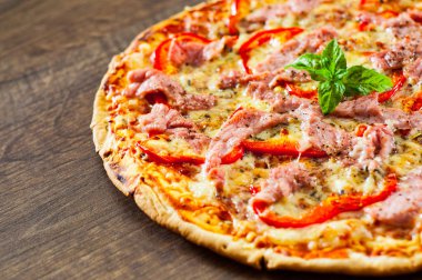 Pizza Mozzarella peyniri, jambon, biber, et, domates, baharat ve taze fesleğen. Ahşap arka plan üzerinde İtalyan pizza