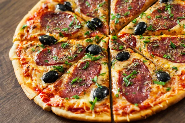 slices of Pizza with Mozzarella cheese, salami, pepper, pepperoni, olives, Spices and Fresh Basil. Italian pizza on wooden background