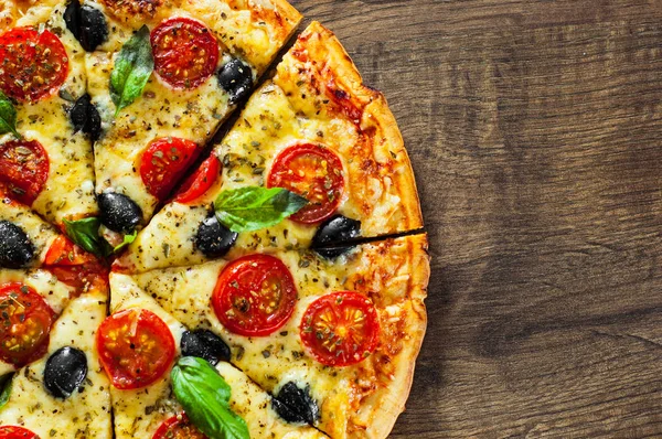 dilimlenmiş Pizza Margherita veya Mozzarella peyniri, domates, zeytin ile Margarita. Ahşap arka plan üzerinde İtalyan pizza