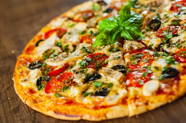 Tavuk eti, Mozzarella peyniri, domates, zeytin dilimlenmiş Pizza. Ahşap arka plan üzerinde İtalyan pizza