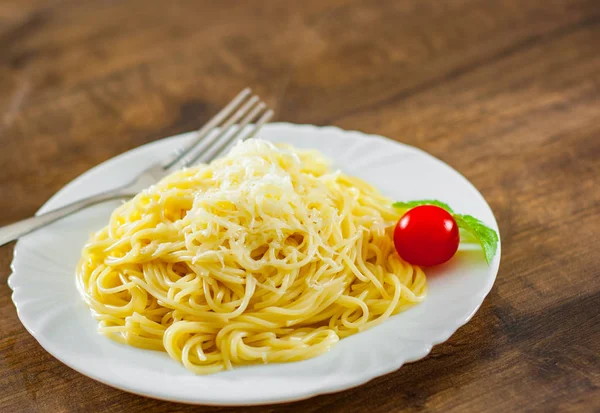 木製テーブルの上の白い皿にチーズをおろしスパゲッティ パスタ — ストック写真