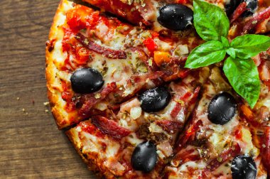 dilim Pizza Mozzarella peyniri, salam, biber, jambon, biber, zeytin, baharat ve taze fesleğen. Ahşap arka plan üzerinde İtalyan pizza