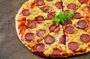 Mozzarella peyniri, salam, domates sosu, biber, baharat ve taze fesleğen ile biberli Pizza. Ahşap arka plan üzerinde İtalyan pizza