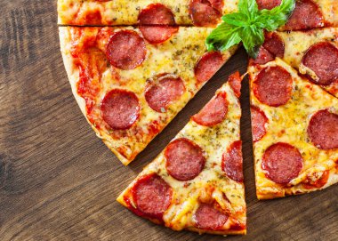 Mozzarella peyniri, salam, domates sosu, biber, baharat ve taze fesleğen ile biberli Pizza. Ahşap arka plan üzerinde İtalyan pizza