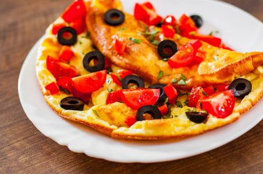 domates, biber ve zeytin ahşap masa arka plan üzerinde beyaz plaka ile omlet