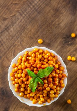 Ahşap masa arka plan üzerinde beyaz kase kızarmış baharatlı nohut