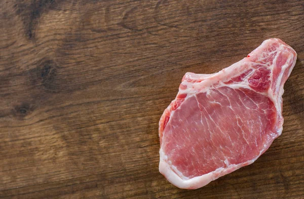 Raw Pork Loin chops meat on wooden table background with copy space. top view