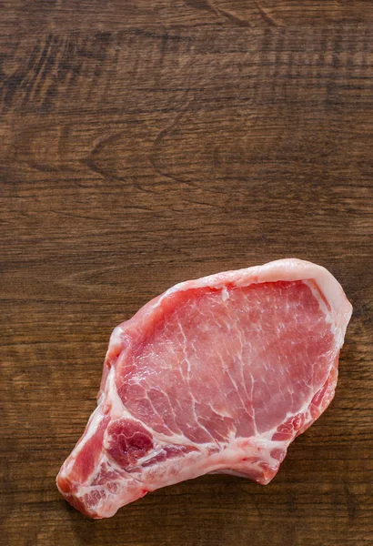 Raw Pork Loin chops meat on wooden table background with copy space. top view