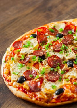 Tavuk eti, Mozzarella peyniri, sucuk, domates, zeytin, salam pizza. Ahşap arka plan üzerinde İtalyan pizza