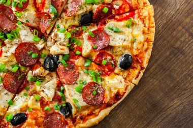 Tavuk eti, Mozzarella peyniri, sucuk, domates, zeytin, salam pizza. Ahşap arka plan üzerinde İtalyan pizza