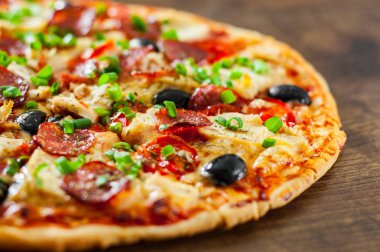 Tavuk eti, Mozzarella peyniri, sucuk, domates, zeytin, salam pizza. Ahşap arka plan üzerinde İtalyan pizza