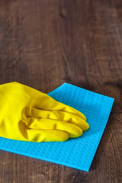 Hand in a glove with a rag cleans wooden floor panels. Cleaning the house.