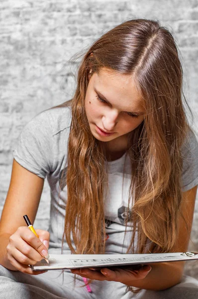 年轻的少年黑发女孩的肖像与长头发画与铅笔在灰色墙壁背景 — 图库照片