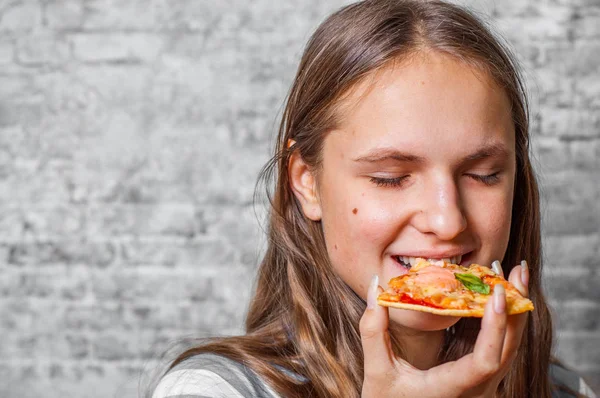 若いですティーンブルネット女の子とともに長いです髪食べるスライスのピザの灰色の壁の背景 — ストック写真