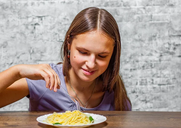 長い髪と灰色の壁の背景にチーズ食べるスパゲッティ パスタの若いティーネー ジャーのブルネットの少女の肖像画 — ストック写真