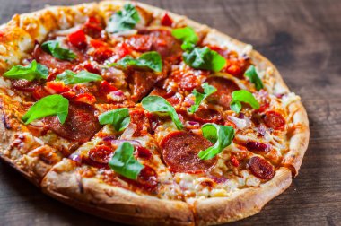 Biberli Pizza dilimlenmiş Mozzarella peyniri, salam, chorizo, salça, biber, baharat ve taze roka. Ahşap masa arka plan üzerinde İtalyan pizza