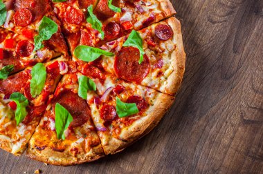 Biberli Pizza dilimlenmiş Mozzarella peyniri, salam, chorizo, salça, biber, baharat ve taze roka. Ahşap masa arka plan üzerinde İtalyan pizza