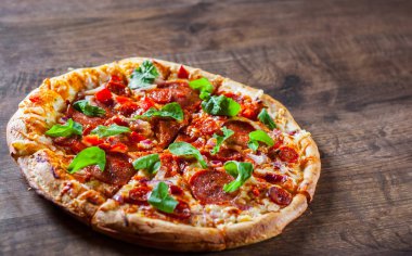 Biberli Pizza dilimlenmiş Mozzarella peyniri, salam, chorizo, salça, biber, baharat ve taze roka. Ahşap masa arka plan üzerinde İtalyan pizza