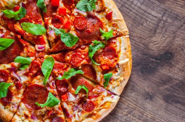 Biberli Pizza dilimlenmiş Mozzarella peyniri, salam, chorizo, salça, biber, baharat ve taze roka. Ahşap masa arka plan üzerinde İtalyan pizza