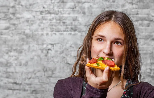 若いですティーンブルネット女の子とともに長いです髪食べるスライスのピザの灰色の壁の背景 — ストック写真