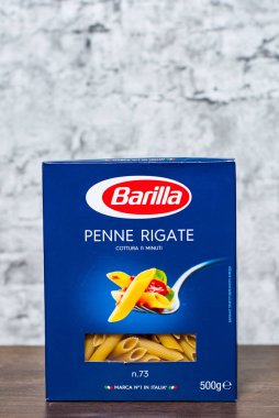 Minsk, Beyaz Rusya - 24 Kasım 2018: Barilla Penne Rigate İtalyan makarna kopya alanı gri duvar zemin üzerine ahşap masa üzerinde bir kutu içinde