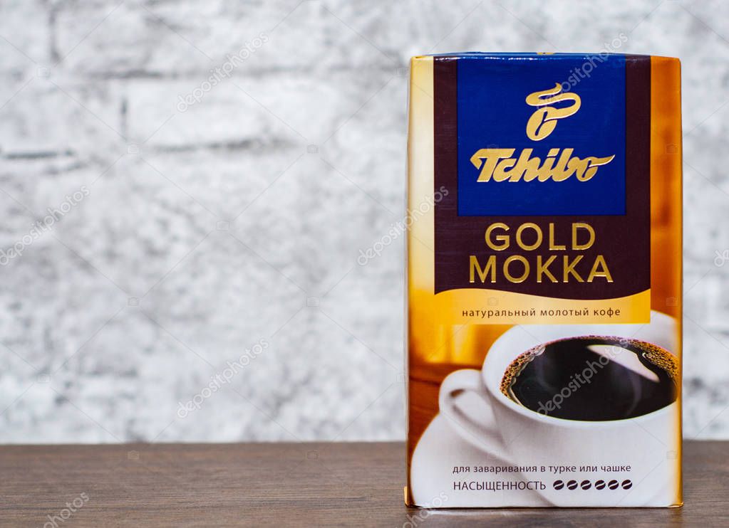 Minsk, Belarus - November 25, 2018:  Studio shot packs of coffee Tchibo gold mokka on wooden table on gray wall background with copy space