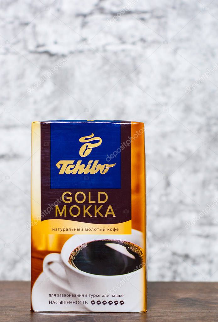 Minsk, Belarus - November 25, 2018:  Studio shot packs of coffee Tchibo gold mokka on wooden table on gray wall background with copy space