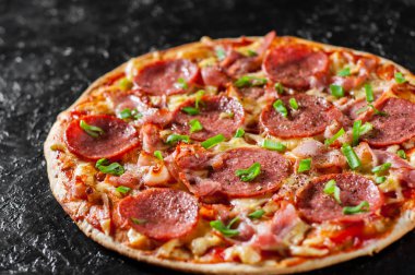 Mozzarella peyniri, salam, pastırma, domates sos, biber, baharat ve taze yeşil soğan ile biberli Pizza. Siyah arka plan üzerine İtalyan pizza