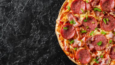 Mozzarella peyniri, salam, pastırma, domates sos, biber, baharat ve taze yeşil soğan ile biberli Pizza. Siyah arka plan üzerine İtalyan pizza