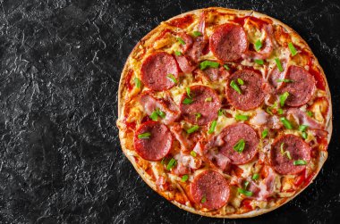 Mozzarella peyniri, salam, pastırma, domates sos, biber, baharat ve taze yeşil soğan ile biberli Pizza. Siyah arka plan üzerine İtalyan pizza