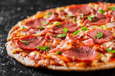 Mozzarella peyniri, salam, pastırma, domates sos, biber, baharat ve taze yeşil soğan ile biberli Pizza. Siyah arka plan üzerine İtalyan pizza