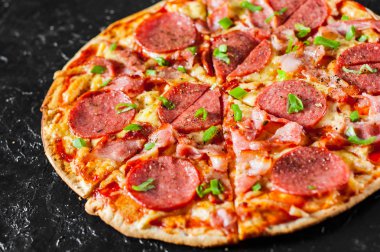 Mozzarella peyniri, salam, pastırma, domates sos, biber, baharat ve taze yeşil soğan ile biberli Pizza. Siyah arka plan üzerine İtalyan pizza
