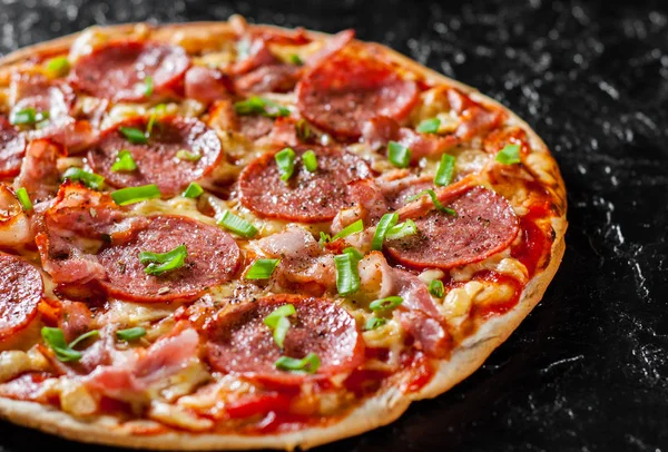 Mozzarella peyniri, salam, pastırma, domates sos, biber, baharat ve taze yeşil soğan ile biberli Pizza. Siyah arka plan üzerine İtalyan pizza