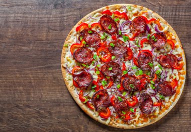 Biberli Pizza Mozzarella peyniri, salam, domates sosu, biber, soğan, baharat. Ahşap masa arka plan üzerinde İtalyan pizza
