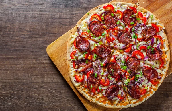 Biberli Pizza Mozzarella peyniri, salam, domates sosu, biber, soğan, baharat. Ahşap masa arka plan üzerinde İtalyan pizza