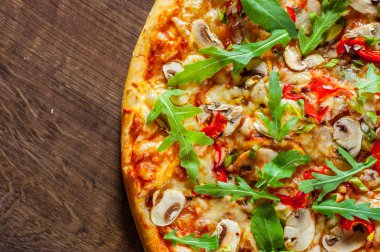 Vejetaryen Pizza Mozzarella peyniri, mantar, domates sosu, biber, baharat ve taze roka. Ahşap masa arka plan üzerinde İtalyan pizza