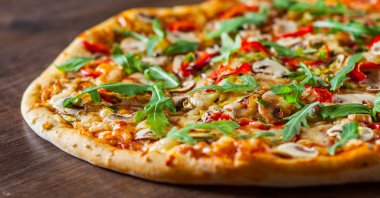 Vejetaryen Pizza Mozzarella peyniri, mantar, domates sosu, biber, baharat ve taze roka. Ahşap masa arka plan üzerinde İtalyan pizza