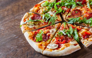 Pizza Mozzarella peyniri, mantar, biber, domates sosu, salam, biber, baharat ve taze roka. Ahşap masa arka plan üzerinde İtalyan pizza