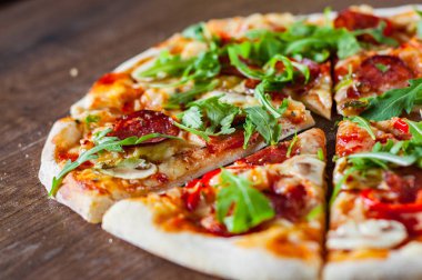 Pizza Mozzarella peyniri, mantar, biber, domates sosu, salam, biber, baharat ve taze roka. Ahşap masa arka plan üzerinde İtalyan pizza