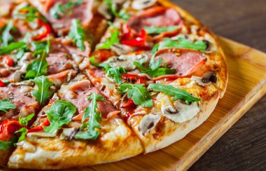 Pizza Mozzarella peyniri, mantar, jambon, domates sosu, salam, biber, baharat ve taze roka. Ahşap masa arka plan üzerinde İtalyan pizza