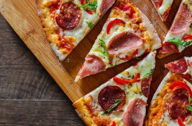 Mozzarella peynirli, jambonlu, domates soslu, salamlı, biberli, baharatlı ve taze roka soslu pizza. İtalyan pizzası ahşap masa arkasında