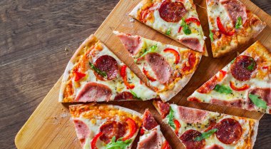 Mozzarella peynirli, jambonlu, domates soslu, salamlı, biberli, baharatlı ve taze roka soslu pizza. İtalyan pizzası ahşap masa arkasında