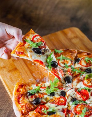 Kadın el Pizza Margherita veya Margarita bir dilim Mozzarella peyniri, domates, zeytin ile alır. Ahşap masa arka plan üzerinde İtalyan pizza