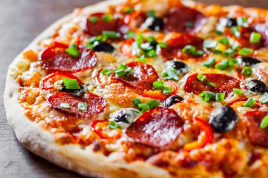 Pizza Mozzarella peyniri, sucuk, domates, biber, zeytin, salam. Ahşap masa arka plan üzerinde İtalyan pizza