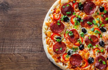 Pizza Mozzarella peyniri, sucuk, domates, biber, zeytin, salam. Ahşap masa arka plan üzerinde İtalyan pizza