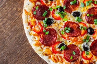 Pizza Mozzarella peyniri, sucuk, domates, biber, zeytin, salam. Ahşap masa arka plan üzerinde İtalyan pizza
