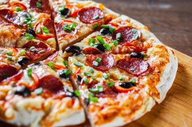 Pizza Mozzarella peyniri, sucuk, domates, biber, zeytin, salam. Ahşap masa arka plan üzerinde İtalyan pizza