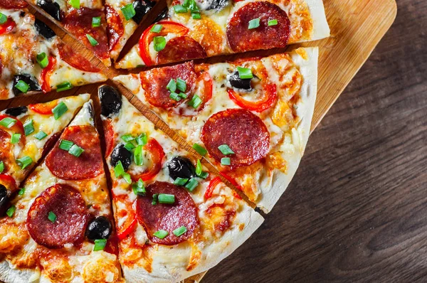 Pizza Mozzarella peyniri, sucuk, domates, biber, zeytin, salam. Ahşap masa arka plan üzerinde İtalyan pizza