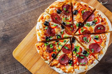 Pizza Mozzarella peyniri, sucuk, domates, biber, zeytin, salam. Ahşap masa arka plan üzerinde İtalyan pizza