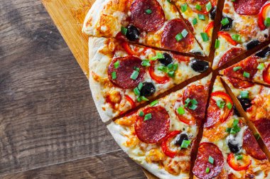 Pizza Mozzarella peyniri, sucuk, domates, biber, zeytin, salam. Ahşap masa arka plan üzerinde İtalyan pizza